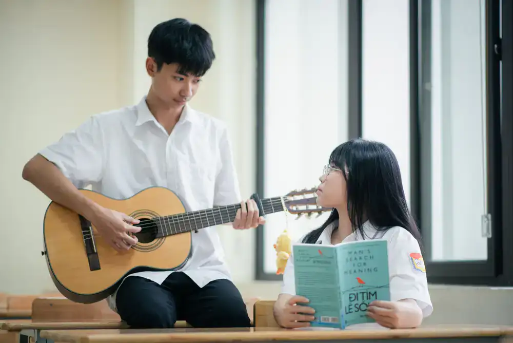 Student smiling while playing acoustic guitar