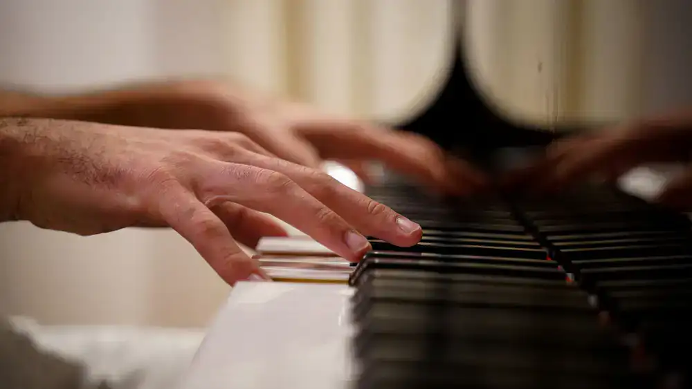 Hands playing a grand piano