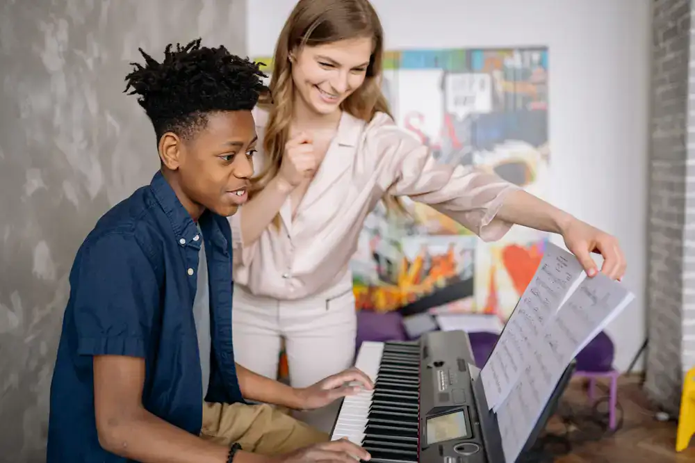 Music teacher guiding a student at the piano
